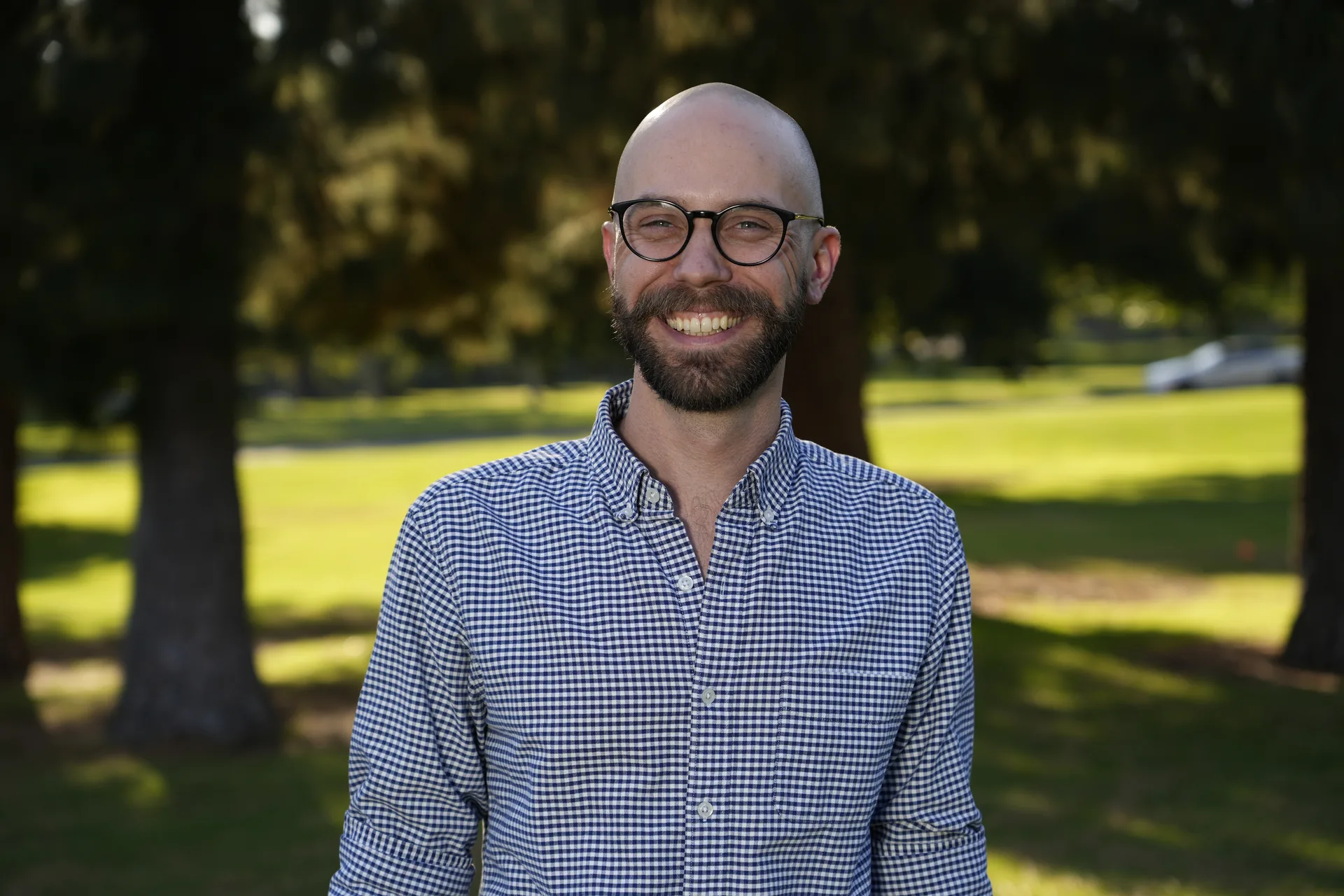 On-site team headshot of a man wearing glasses, photographed outdoors