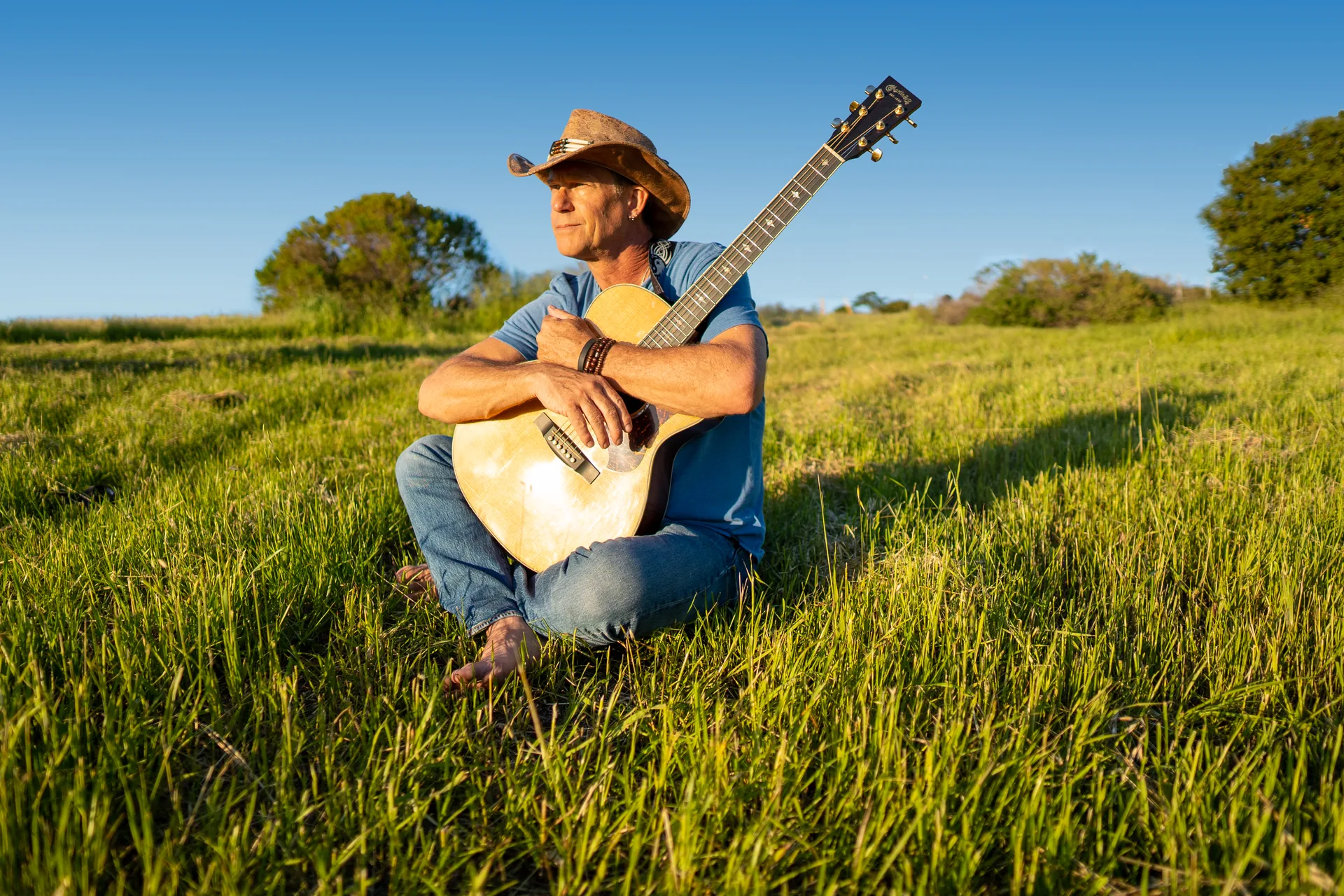 Musician portrait with an acoustic guitar in an open field
