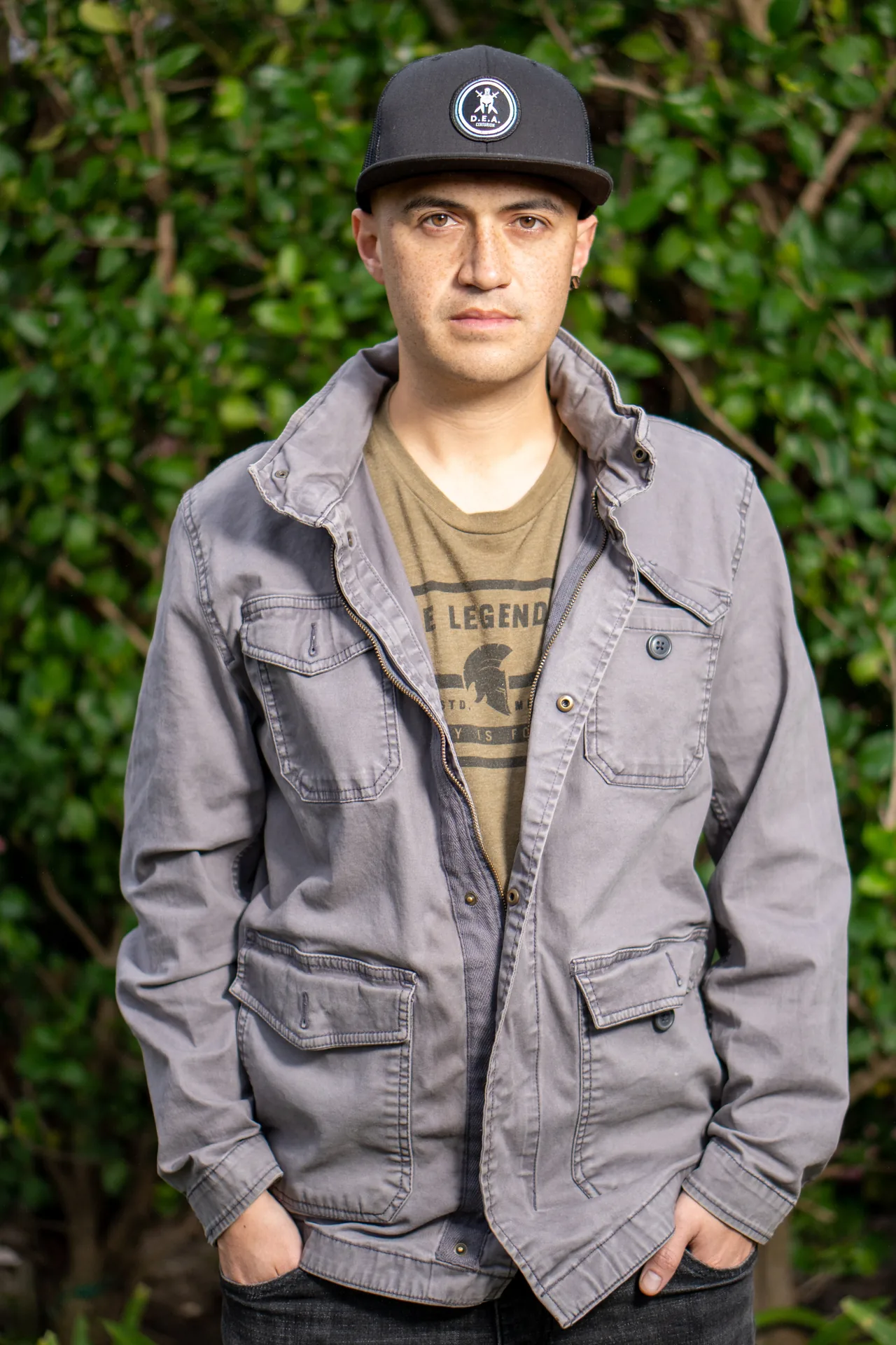 Professional headshot of a person in a utility jacket on a grey background