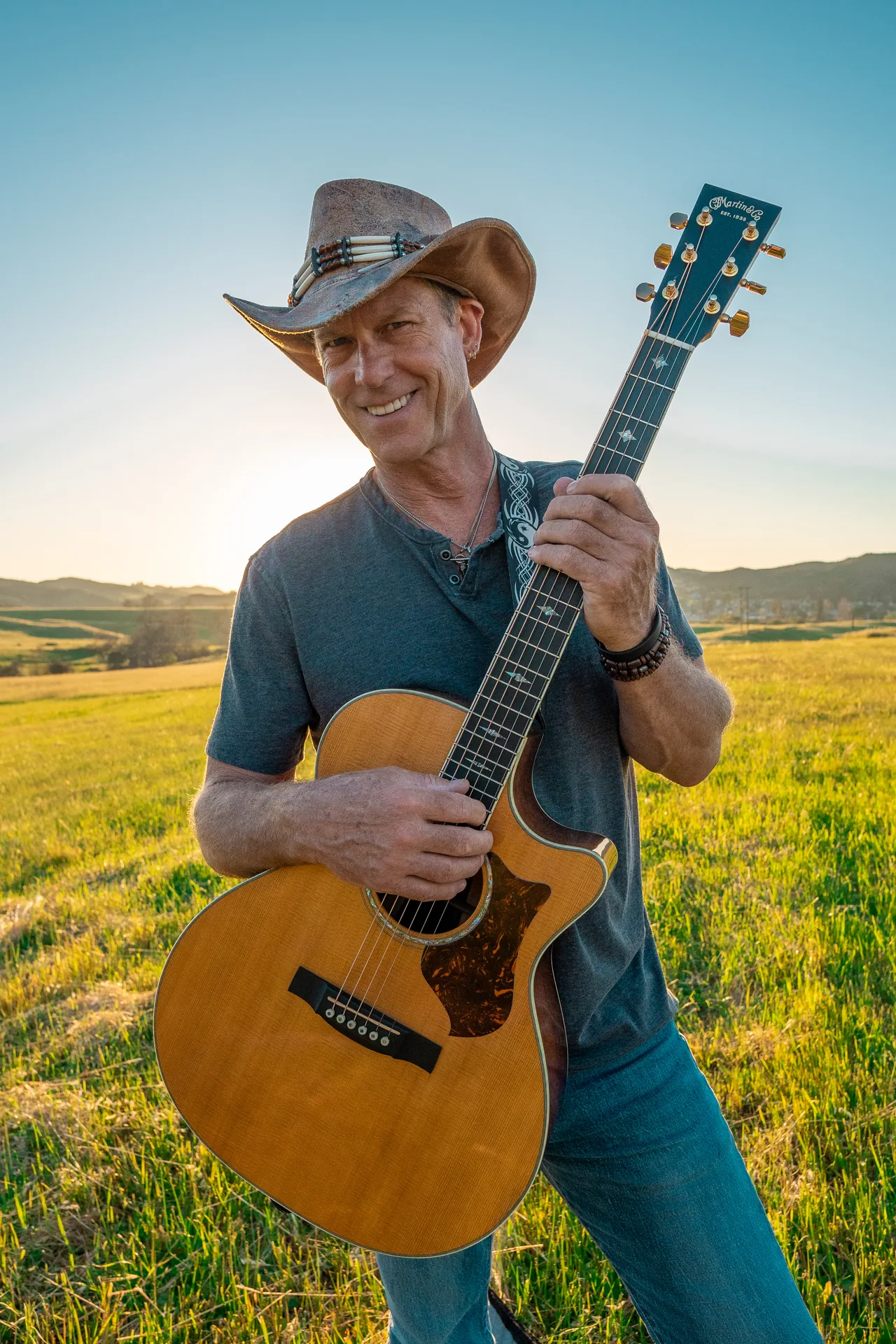 Musician portrait with an acoustic guitar photographed in an open field